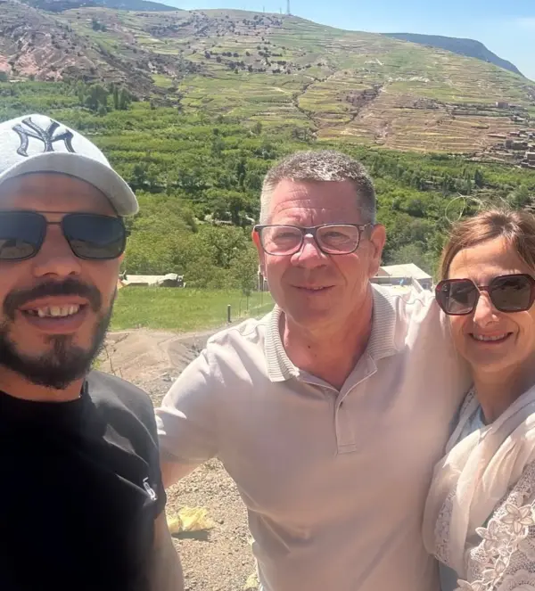 Un chauffeur Chams avec deux voyageurs devant les cultures en terrasses du Haut Atlas