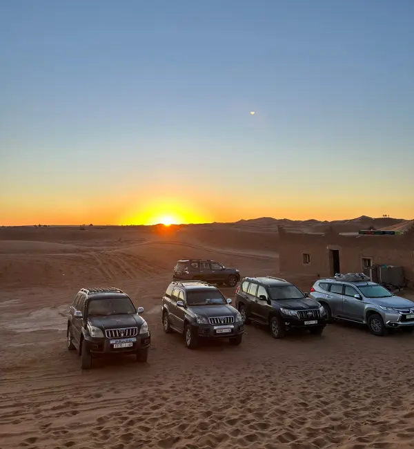 Toyota Land Cruiser Prado garés dans les dunes de Merzouga au coucher du soleil