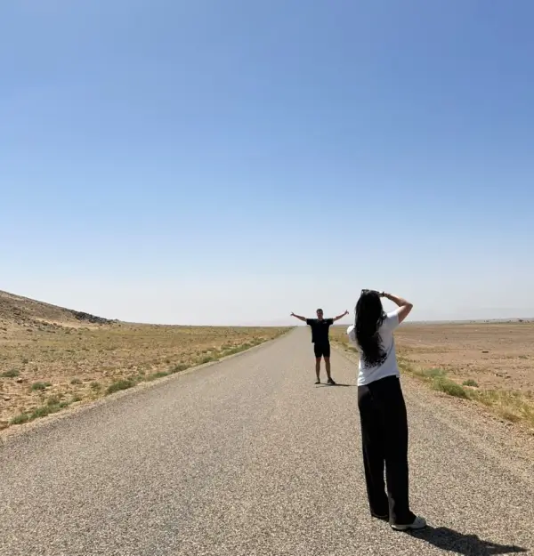 Une voyageuse photographie son ami sur une longue route déserte du sud marocain